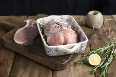 bir fırın tepsisine limon ve biberiye, ahşap masa ve havlu ile ip ile et bağlı