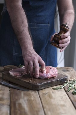 bir adam bir mutfak önlük et tutan elleri ve tuz, ahşap bir masa ve baharatlar