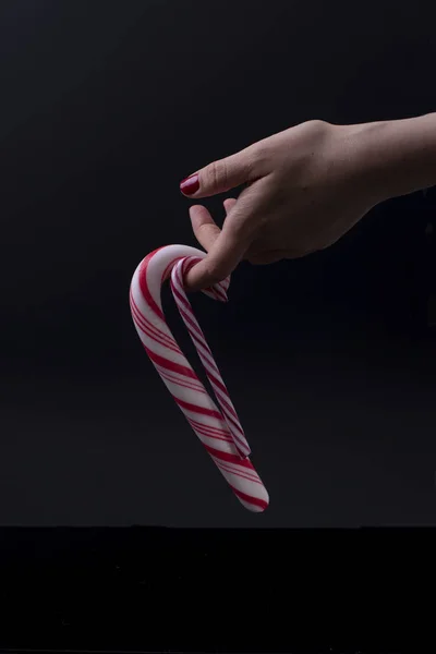 Дві різдвяні цукерки в жіночій руці на чорному тлі — стокове фото