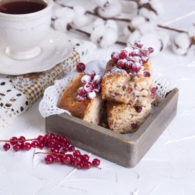 çay ve uçan daire, ahşap masa ve beyaz arka plan, pamuk çiçek üzerinde kırmızı kuş üzümü ile cupcake fincan.