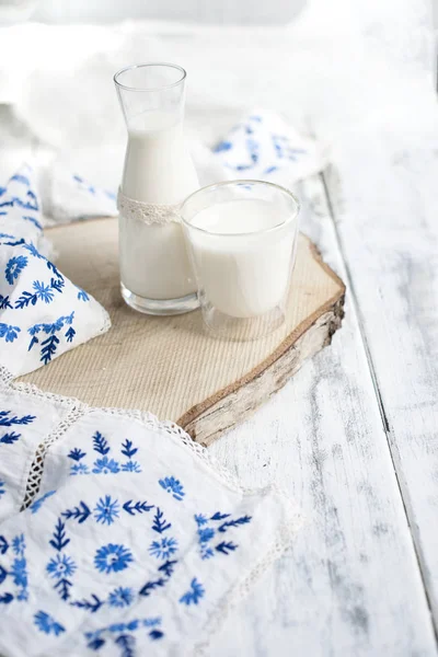 Egy pohár tejet, és egy üveg tejet. Egy pamut ág és törölköző hímzett kék virágok. Fehér háttér és a szöveg-vagy dekorációs szabad hely — Stock Fotó