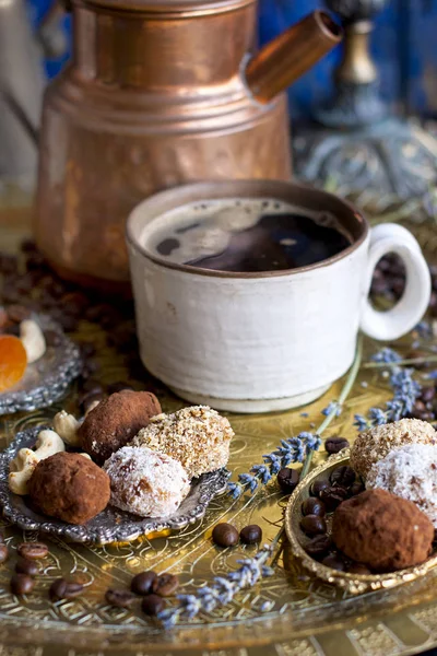 The coffee pot pours the coffee into the cup. in the oriental style. handmade candies, dried fruits and flowers. photo in the style of dark. brassware and ceramics.