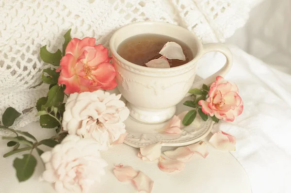 Ароматний чай в старовинному кухоль і рожеві троянди, смачний і красивий сніданок. Пастельні відтінки — стокове фото