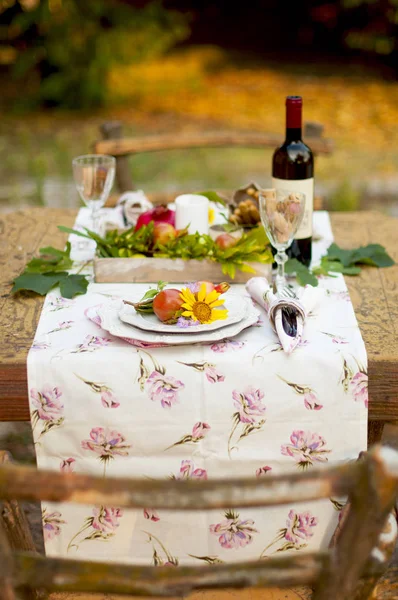 Romantic dinner in the autumn garden, table setting for a nice dinner. Wine, fruit, pomegranate and flowers. Picnic in the open air. — Stock Photo, Image