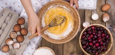 Kiraz ile ev yapımı tatlı hamur işleri hazırlanması. Yumurta, un ve çilek ahşap arka plan üzerinde. Çerçeve elinde. Düz yatıyordu,