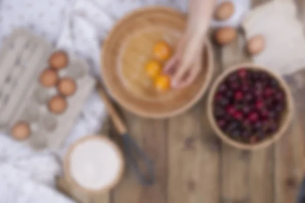 Приготування домашньої солодкої випічки з вишнями. Яйця, борошно та ягоди на дерев'яному фоні. Жіночі руки розділяють яйця на дерев'яну миску. Копіювати простір — стокове фото