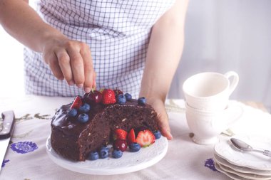 Beyaz arka plan üzerinde taze çilek ile çikolatalı kek. Bir kız bir pasta onun elinde tutuyor. Şekerli tatlı. Kopya alanı