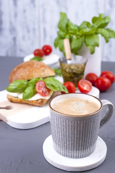 Ароматный утренний кофе и сэндвич с моцареллой, песто-соус с базиликом на завтрак. Вкусная и здоровая еда. Итальянский обед. Вид сверху, пространство для копирования — стоковое фото