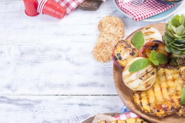 Piknik ızgara gıda ile. ananas, şeftali ve barbekü Mısır. Lezzetli yaz öğle ve plastik yemekleri. Üstten görünüm.