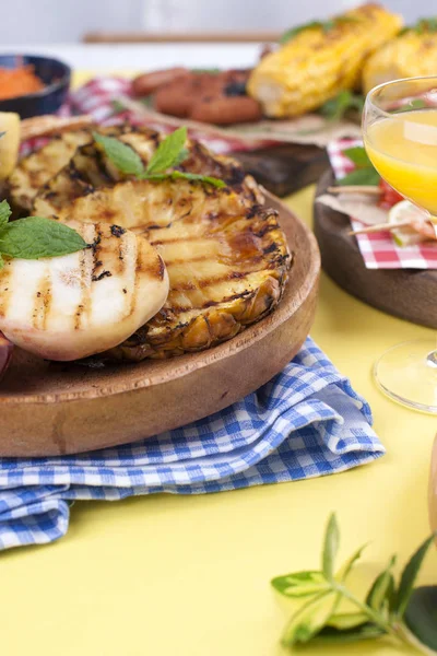 Picnic con cibo grigliato. Salsicce e mais su barbecue, gamberetti, verdure e frutta. Delizioso pranzo estivo e piatti di plastica. Vista dall'alto . — Foto Stock