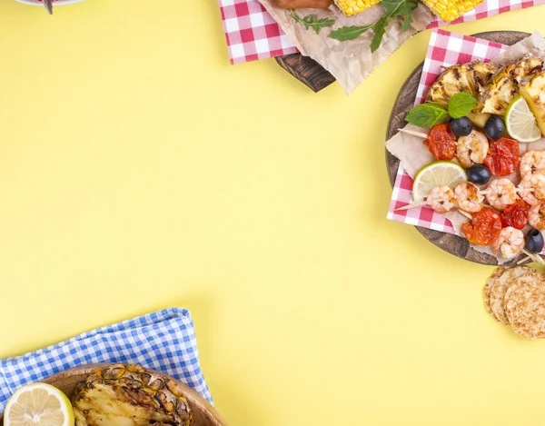 Пікнік з стравами на грилі. Сосиски та кукурудза на барбекю, креветки, овочі та фрукти. Смачний літній обід і пластикові страви. Вид зверху . — стокове фото