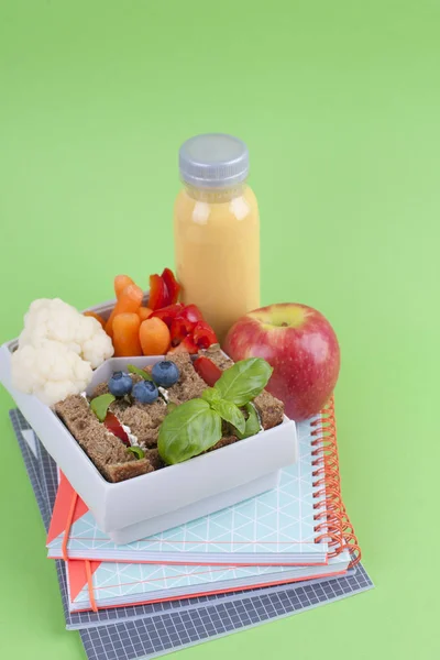 Almuerzo escolar en el contenedor. Sandwich con queso y verduras, fruta y jugo fresco. Un almuerzo saludable para los niños. Vista superior . — Foto de Stock