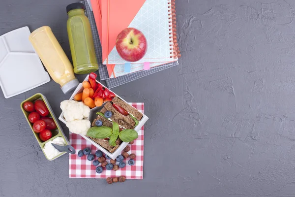 Almuerzo escolar en el contenedor. Sandwich con queso y verduras, fruta y jugo fresco. Un almuerzo saludable para los niños. Vista superior . —  Fotos de Stock