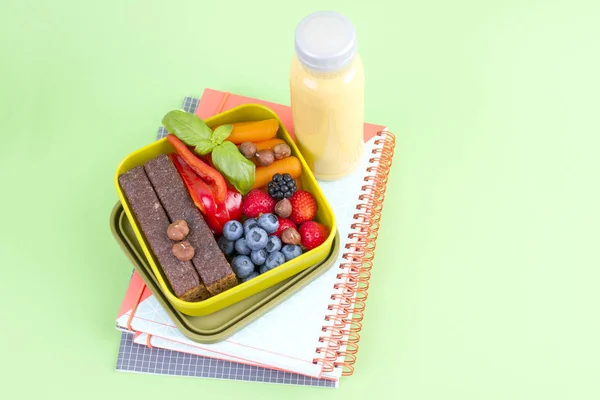 Delicioso desayuno holandés con pan dulce, bayas y jugo en una botella. Almuerzo para escuela y oficina. Accesorios escolares y libros de ejercicios. Vista superior . —  Fotos de Stock