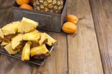 Ananas ve ahşap arka plan üzerinde metal bir kutu şeftali. Vitamin ve detoks yaz aylarında. Vintage Fotoğraf. Polis alanı