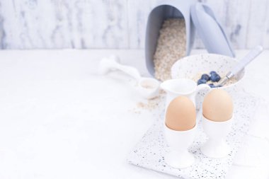 Haşlanmış yumurta Kahvaltı, yulaf lapası çilek ve sütle hafif bir arka plan üzerinde beyaz yemekler için. Lezzetli ve sağlıklı bir kahvaltı. Metin için özgür yer. Üstten görünüm. Kopya alanı