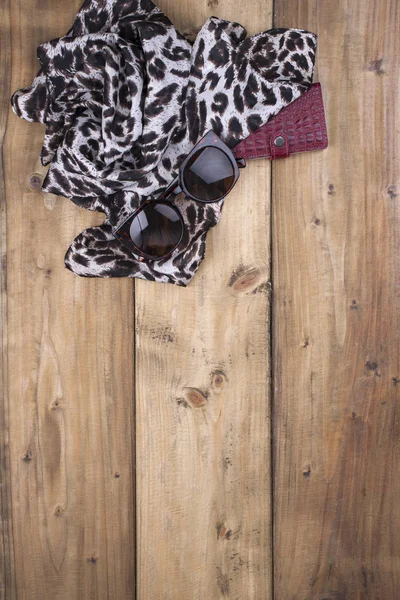 Szalik z leopard print, okulary i torebki czerwone skórzane na tle drewnianych. Naturalne kolory i naturalny ornament w modzie. Ilość wolnego miejsca dla tekstu. Widok z góry. — Zdjęcie stockowe