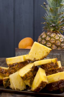 Ananas ve ahşap arka plan üzerinde metal bir kutu şeftali. Vintage Fotoğraf. Kopya alanı