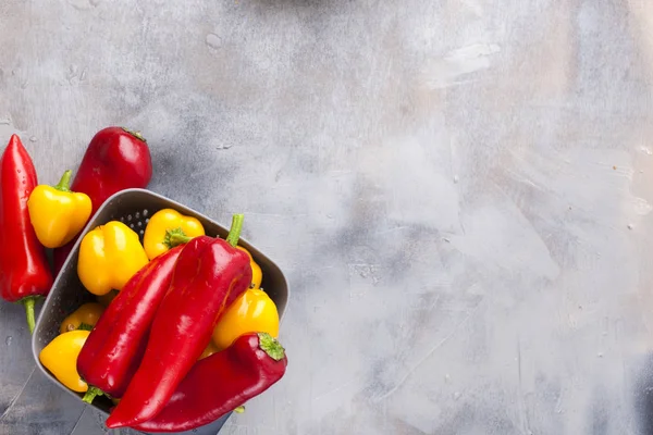 Tatlı biber sarı ve kırmızı, gri bir arka plan üzerinde. Alan için metin, çerçeve. Üstten görünüm