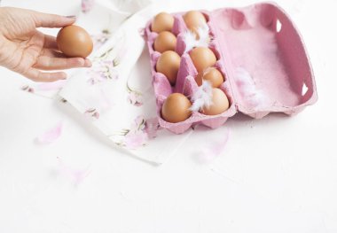 Pembe kutu tavuk yumurtası ile. Peara ve dekorasyon için çiçekli havlu. Yumurta beyaz arka plan ve çerçeve elinde. Paskalya için. Üstten görünüm.