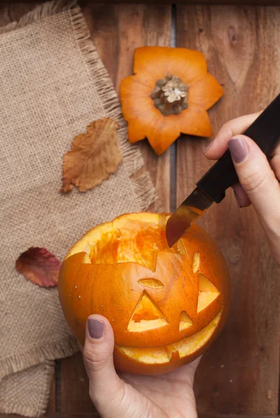 Dýně na Halloween v rukou Dámské, příprava na podzimní dovolenou. Listy a výzdoba na dřevěný stůl. Pohled shora. — Stock fotografie