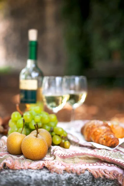 Una botella de vino y dos vasos, en un picnic. Hojas de otoño en el jardín. Fiesta romántica en la calle. Espacio libre para texto. Copiar espacio . — Foto de Stock