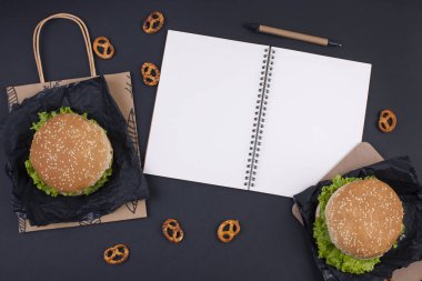 Hamburger yemeğe siyah bir zemin üzerine. Metin ve planlama için not etmek. Fast food ve aperatifler ofis ve okul için. Düz yatıyordu. Kopya alanı.