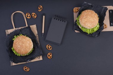 Öğle yemeği için siyah bir zemin üzerine iki hamburger. Fast Food ve aperatifler ofis ve okul. Üstten görünüm. Metin için özgür yer. Fkat lay.