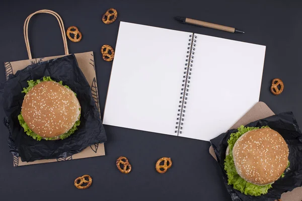 Hamburger yemeğe siyah bir zemin üzerine. Metin ve planlama için not etmek. Fast food ve aperatifler ofis ve okul için. Düz yatıyordu. Kopya alanı.