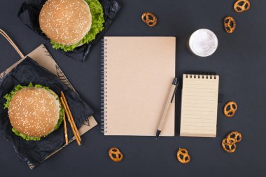 Öğle yemeği için siyah bir zemin üzerine iki hamburger. Fast Food ve aperatifler ofis ve okul. Üstten görünüm. Metin için özgür yer. Fkat lay.