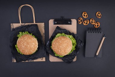 Öğle yemeği için siyah bir zemin üzerine iki hamburger. Ofis ve okul gıda. Üstten görünüm. Metin için özgür yer. Düz yatıyordu.