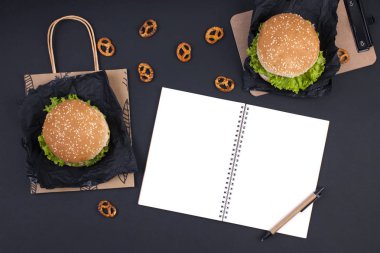 Öğle yemeği için siyah bir zemin üzerine iki hamburger. Ofis ve okul gıda. Üstten görünüm. Metin için özgür yer. Düz yatıyordu