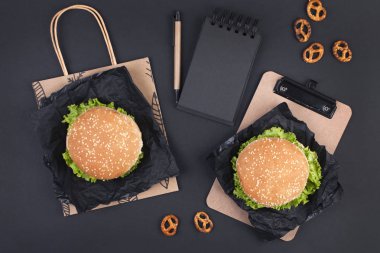 Öğle yemeği için siyah bir zemin üzerine iki hamburger. Ofis ve okul gıda. Üstten görünüm. Metin için özgür yer. Düz yatıyordu