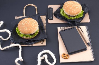 Öğle yemeği için siyah bir zemin üzerine iki hamburger. Ofis ve okul gıda. Üstten görünüm. Metin için özgür yer. Düz yatıyordu