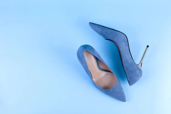 Blue suede stilettos. On a blue background. Women\'s elegant shoes. Free space for text. Hard light on the photo
