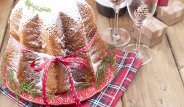 Geleneksel İtalyan Noel meyve Panettone Pandoro Festival kırmızı kurdele ve Noel süslemeleri ile pasta. Ahşap bir arka plan üzerinde. Metin için boş alan