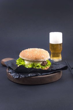 Büyük hamburger, bira ve bir siyah arka plan üzerinde planlama için defter. Fast food ve aperatifler. Metin için özgür yer. Düz yatıyordu. Kopya alanı