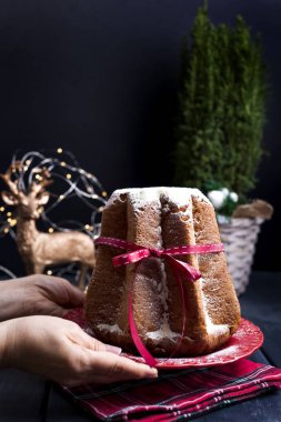 Erkek çerçeve ve İtalyan Pandoro Noel kek limon kremalı eller. Dekor ve tatlılar Noel için. Bir bokeh çelenk ve siyah bir arka plan. Kış tatili