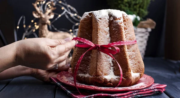 女性的手在框架和意大利潘多罗圣诞蛋糕与柠檬奶油 圣诞节的装饰和糖果 花环上的和黑色的背景 — 图库照片