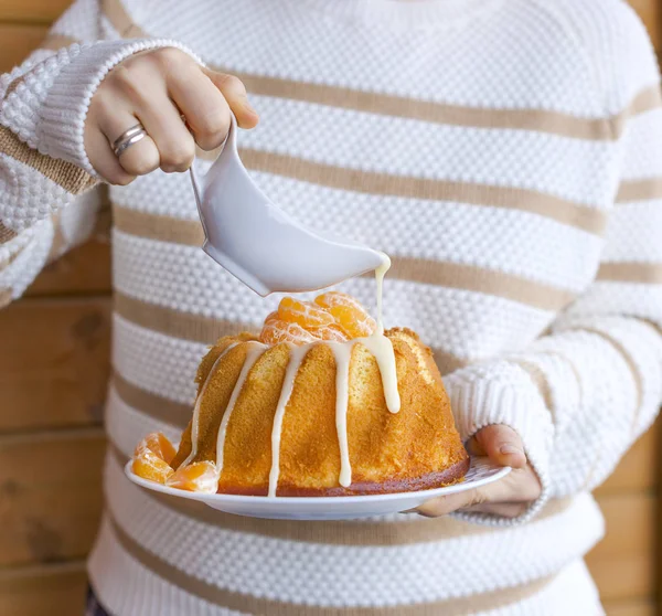 Cupcake with tangerines in female hands. Christmas homemade cakes with icing and fruit. Natural light on the photo. A man in a sweater