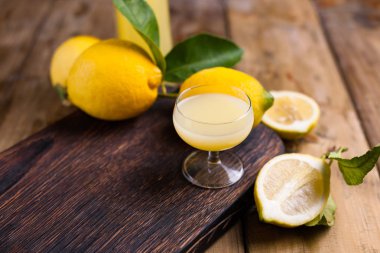 Tahta bir tahtanın üzerinde limoncello ve limonlar. İtalya 'nın geleneksel alkollü içeceği. Turunçgillerden. Taze meyve ve içecekler. Metin için boş alan. Üst görünüm