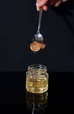 Siyah arka planda bal kavanozunda mantar mantarı. Kompozisyonda minimalizm. Lüks yemekler. Metin için boş alan