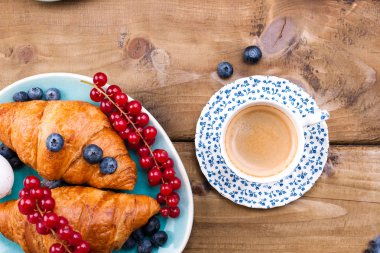 Eski bir fincanda taze aromatik kahve, ev yapımı hamur işi kruvasan.