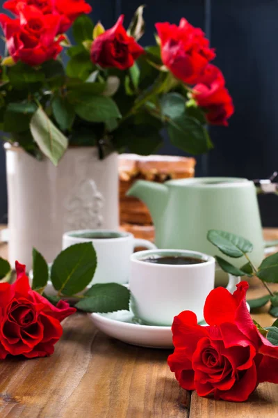 A large bouquet of red roses in a vase, and a cup of tea for a festive breakfast. Romantic Gift for women. The concept of St. Valentine\'s Day and Women\'s Day on March 8. Free space for text