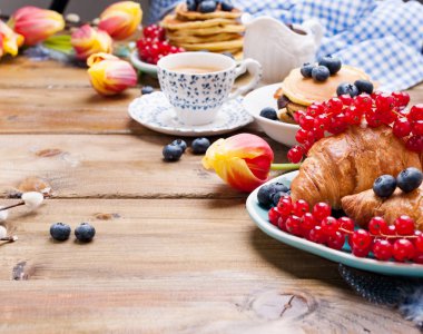 Frenk üzümlü kruvasan ve yaban mersini, ahşap bir masada taze aromatik kahve. Taze tatlı hamur işleriyle Avrupai kahvaltı. Metin için boş alan