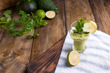 Avokado smoothie ve limon bir bardakta. Sağlık ve güzellik için besin. Sebze ve meyvelerden süper yemek. Ahşap arkaplan, metin için boş alan