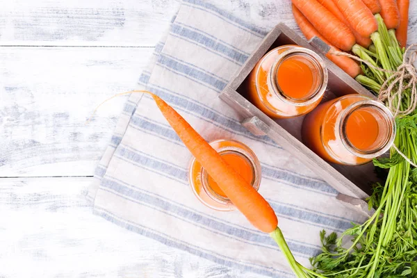 Kavanozda taze havuç suyu. Yapraklı taze havuç ve içecek. Sağlık ve güzellik için bahar yiyeceği. Metin için boş alan. Üst görünüm