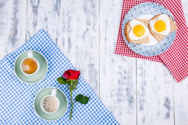 Tabakta kalp şeklinde yumurta ve iki fincan kahveyle tost. İki kişilik romantik kahvaltı. Kahvaltı için kırmızı gül ve sabah sürprizi. Sevgililer Günü ve Anneler Günü konsepti