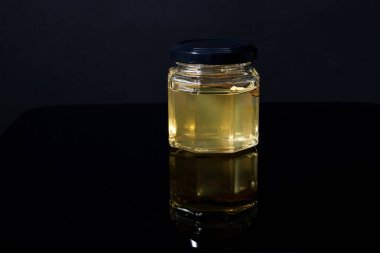 Siyah arka planda bal kavanozunda mantar mantarı. Kompozisyonda minimalizm. Lüks yemekler. Metin için boş alan