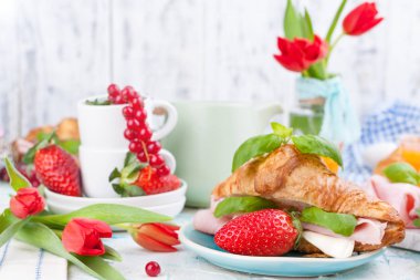 Ayçöreği ve pastırmalı tatlı bahar kahvaltısı. Bir buket kırmızı lale ve taze çilek ve kuşüzümü. Tatil kutlaması konsepti